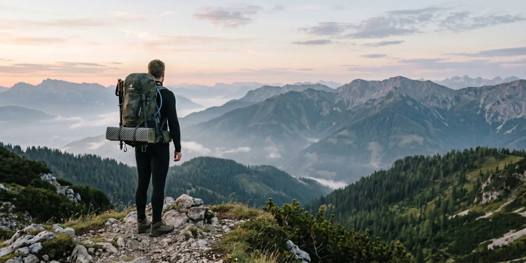 Hiker wearing sustainable merino wool base layer on a mountain ridge at sunrise